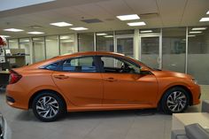 an orange car is parked in a showroom