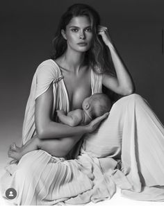 a woman sitting on the ground holding a baby