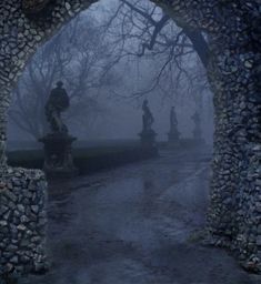 an archway with statues in the middle of it and foggy sky behind them at night