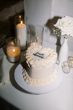 a white cake sitting on top of a table next to candles