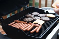 hot dogs, hamburgers and cheese are being cooked on the bbq with tongs