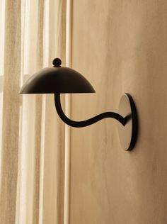 a black wall light mounted on the side of a wall next to a white curtain