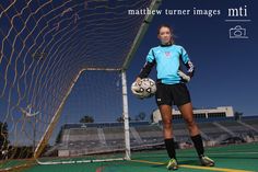 a female soccer player holding a ball in front of a goalie's net