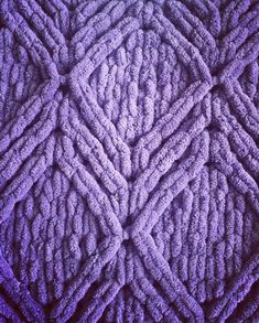 a close up view of a purple crochet pattern on a blanket that has been made with yarn