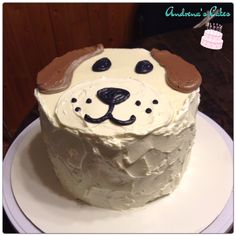 a cake with white frosting and brown dog's head on top is sitting on a plate