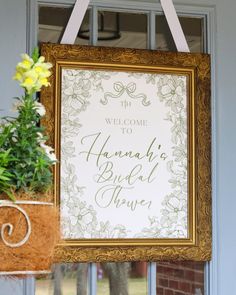 a welcome sign hanging on the front door of a house with flowers in pots next to it