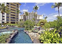 an outdoor hot tub surrounded by palm trees and other greenery in front of a hotel