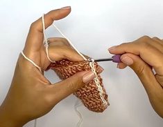 two hands are holding yarn and knitting together