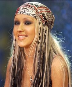 a woman with long hair wearing a bandana and braids on her head is smiling