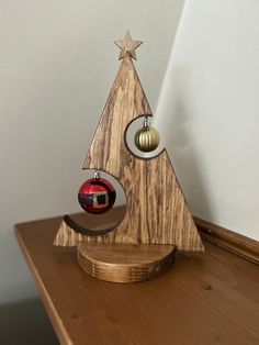 a wooden christmas tree with two ornaments hanging from it's sides on a table