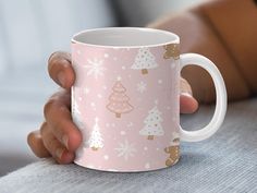 a person holding a pink coffee mug with christmas trees on it