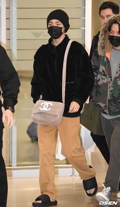 a man wearing a face mask while walking through an airport with other people behind him