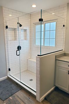 a bathroom with a walk in shower next to a sink and toilet on top of a hard wood floor