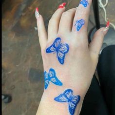 a woman's hand with blue butterflies painted on it