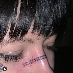 a close up of a person's face with tattoos on their forehead and behind his ear