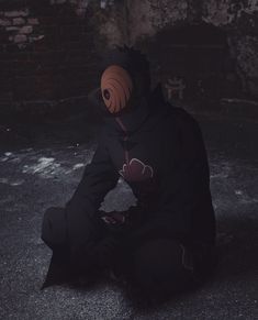 a person sitting on the ground wearing a black outfit