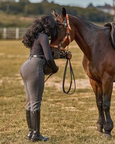 a woman standing next to a brown horse