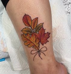 a woman's foot with a leaf tattoo on the side of her leg that has a bow tied around it