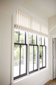 an empty room with three windows and a rug on the floor