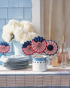 the table is set with plates, cups and vases in red, white, and blue colors