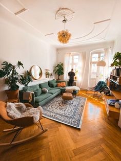 a living room filled with lots of furniture and plants on top of wooden flooring