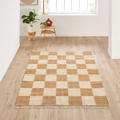 a checkered rug is in the middle of a room with white walls and wooden floors