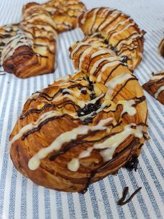 several donuts with icing and chocolate drizzles on a striped table cloth