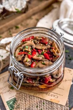 a glass jar filled with food sitting on top of a wooden table next to papers