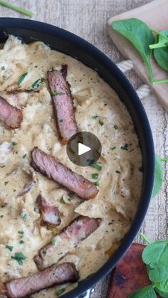 a skillet filled with meat and gravy on top of a wooden table