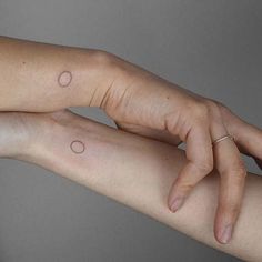 two hands holding each other with small dots on their wrist tattoo designs for women and men