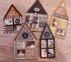 three small houses made out of scrapbook pages on top of a wooden table next to each other