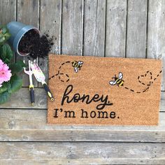 a door mat that says honey i'm home next to flowers and gardening tools