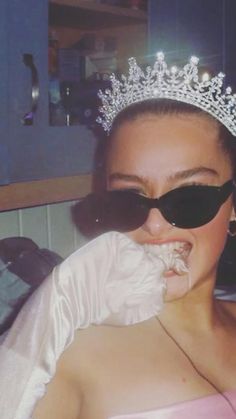 a woman wearing a tiara and gloves with her mouth covered in white frosting