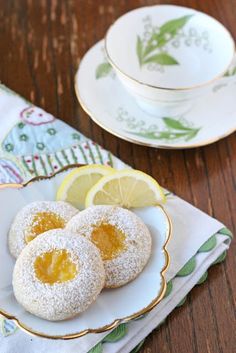 two lemon cookies are on a plate next to a cup and saucer