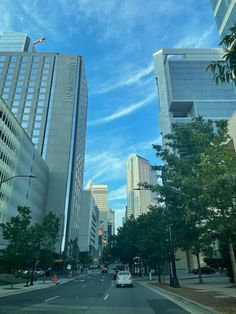 a city street lined with tall buildings under a blue sky filled with wispy clouds