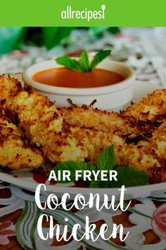 air fryer coconut chicken on a plate with dipping sauce and green leafy garnish