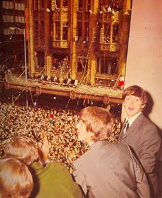 two boys are standing in front of a crowd looking at the stage from behind them