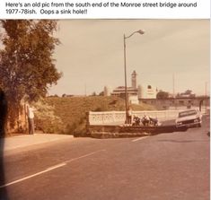 an old black and white photo of people standing on the side of a road next to a bridge