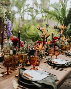 the table is set with candles, plates and place settings for an outdoor dinner party