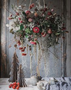 an arrangement of flowers and branches hanging from the ceiling