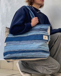 a woman sitting on the floor holding a blue striped bag