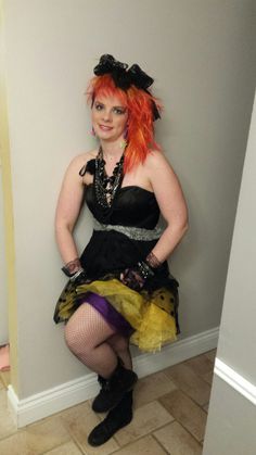 a woman with red hair wearing a black and yellow dress is posing for the camera