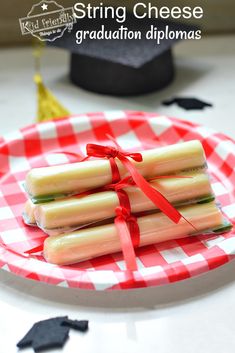 three pieces of cheese wrapped in red ribbon on a plate with graduation cap and tassel