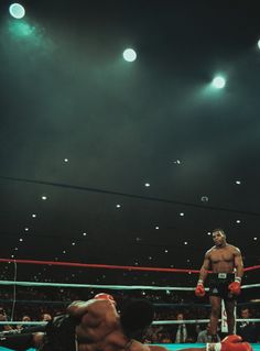 a man standing on top of a wrestling ring next to another person in the ring