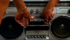 two hands on top of a boombox with radio and speakers in front of it