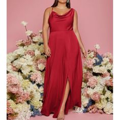 a woman standing in front of flowers wearing a red dress with one leg slited