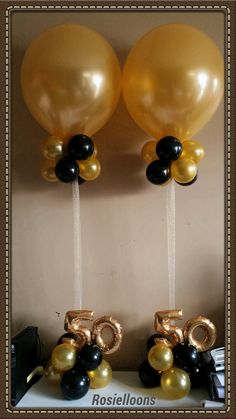 two balloons with the number 50 on them and some black, gold and white balloons