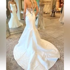 a woman standing in front of a mirror wearing a wedding dress