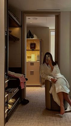 a woman taking a selfie while sitting on a chair in a hotel room,