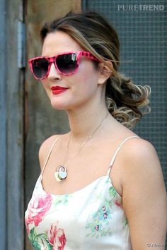 a woman wearing pink sunglasses is walking down the street